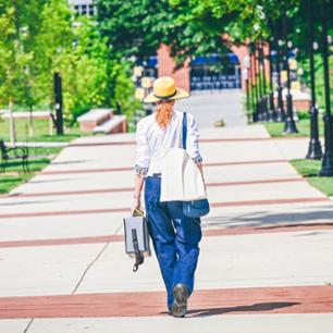 A student walks across the ETSU Commons on a sunny day.
