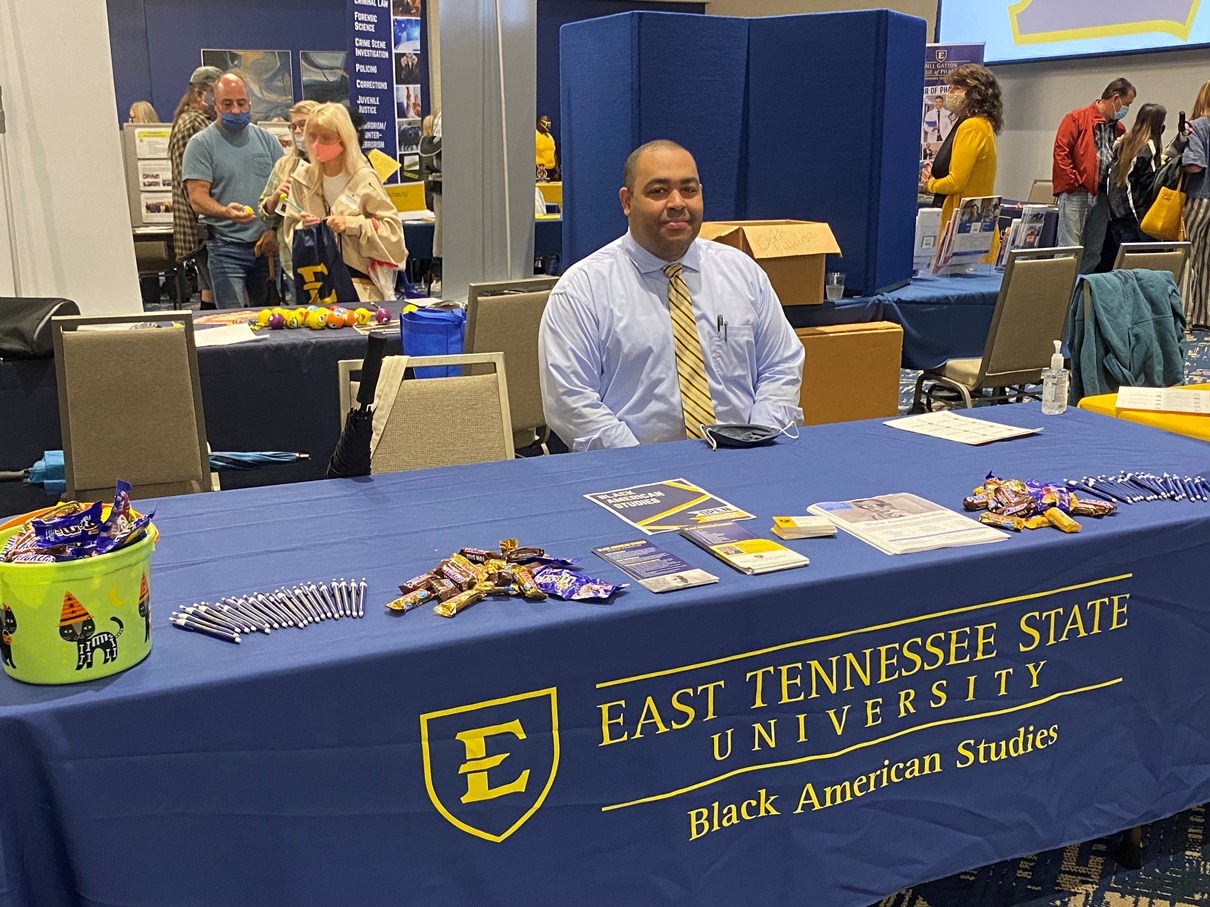 Dr. Carter seated at an open house table with Black American Studies information and candy.