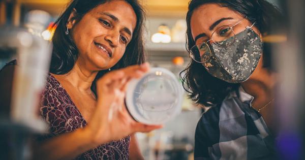 A professor and student gaze into the contents of a petri dish