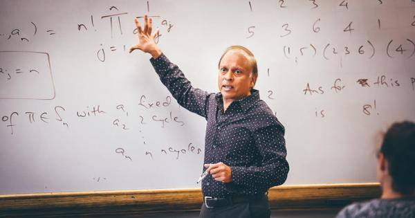 A mathematics professor showing equations to his classroom on a white board