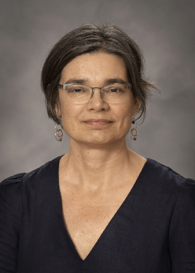 A woman with ear-length, dark hair, in a navy blue top and glasses.