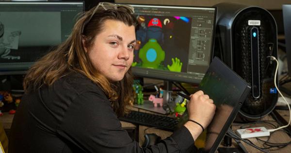 A student turns from a program open on their computer screen to look at you. This is a digital media class.