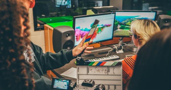 Two ETSU Media and Communications students looking at screens and using a film clapboard