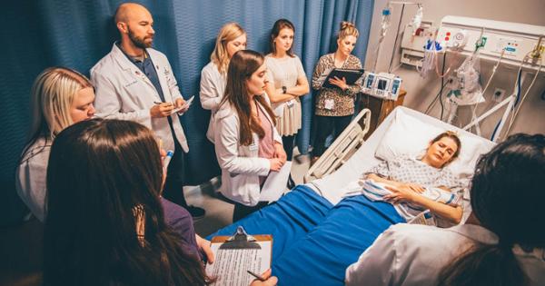 A group of interns surrounding a pretend patient in a clinic setting