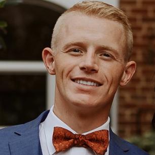 Matt Hensley smiling broadly with red bowtie and blue suit. 