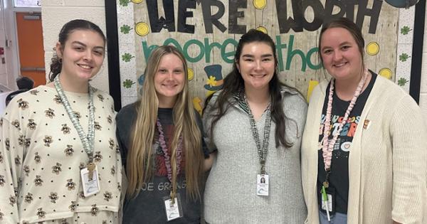 Four female teachers posing together and smiling while wearing pajamas.