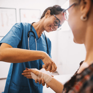 Rheumatologist wrapping a patient in bandage on her wrist.
