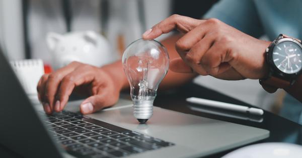 Person balances a lightbulb on top of a laptop's mouse pad