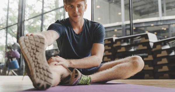 Young adult male stretches on yoga mat