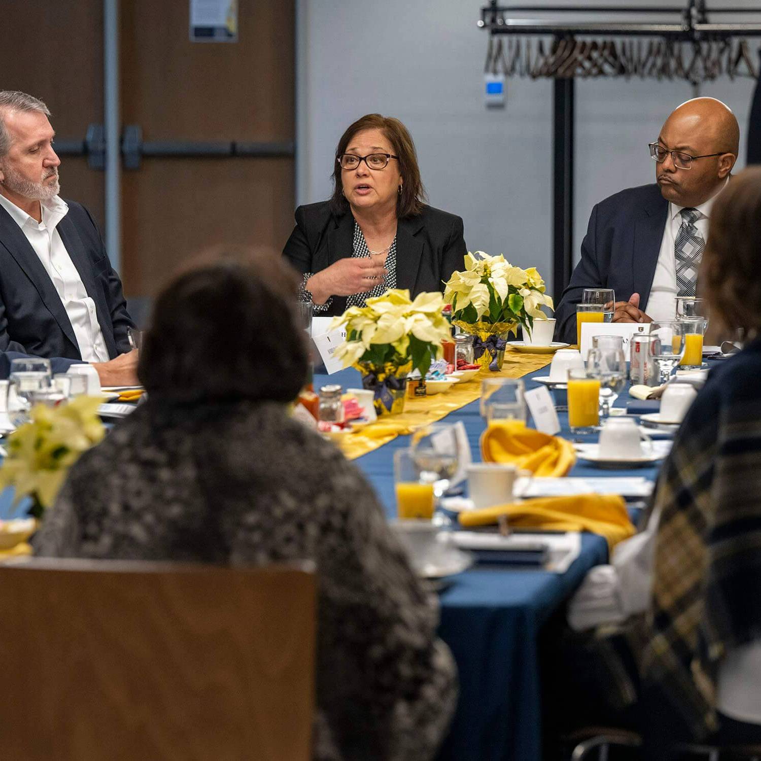 Group of community partners talk around a breakfast table.