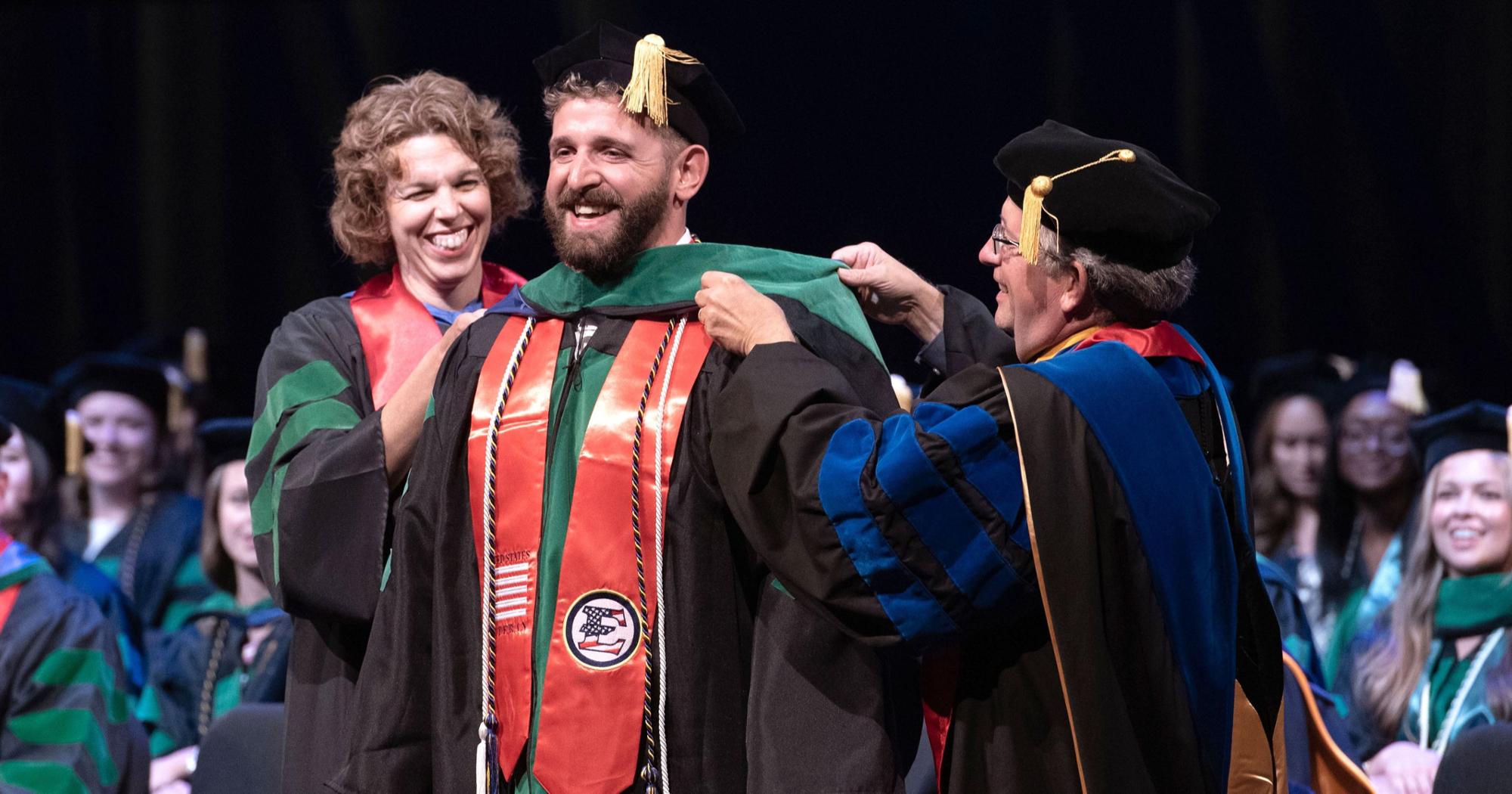 A Quillen graduate smiles while being hooded.