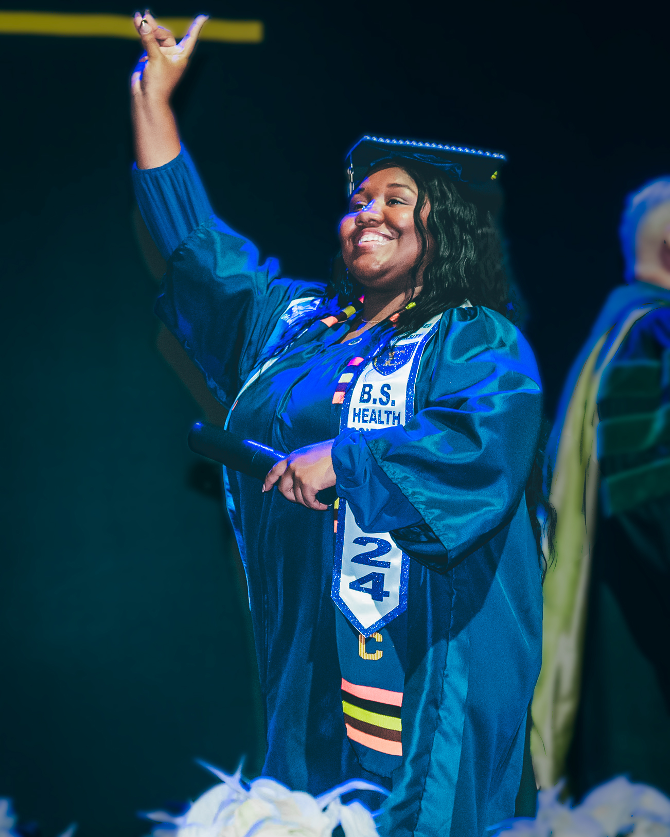 A graduate lifts her diploma in celebration as she crosses the stage at commencement