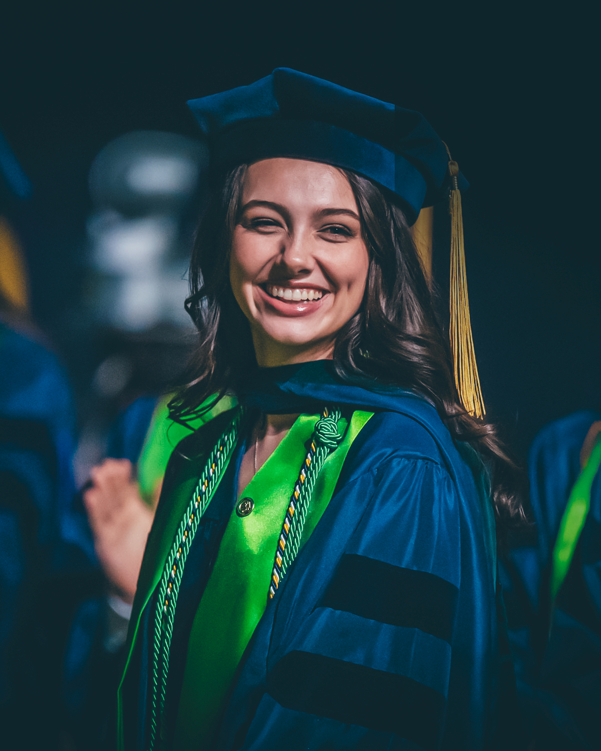 An ETSU graduate smiles while cheering on her classmates