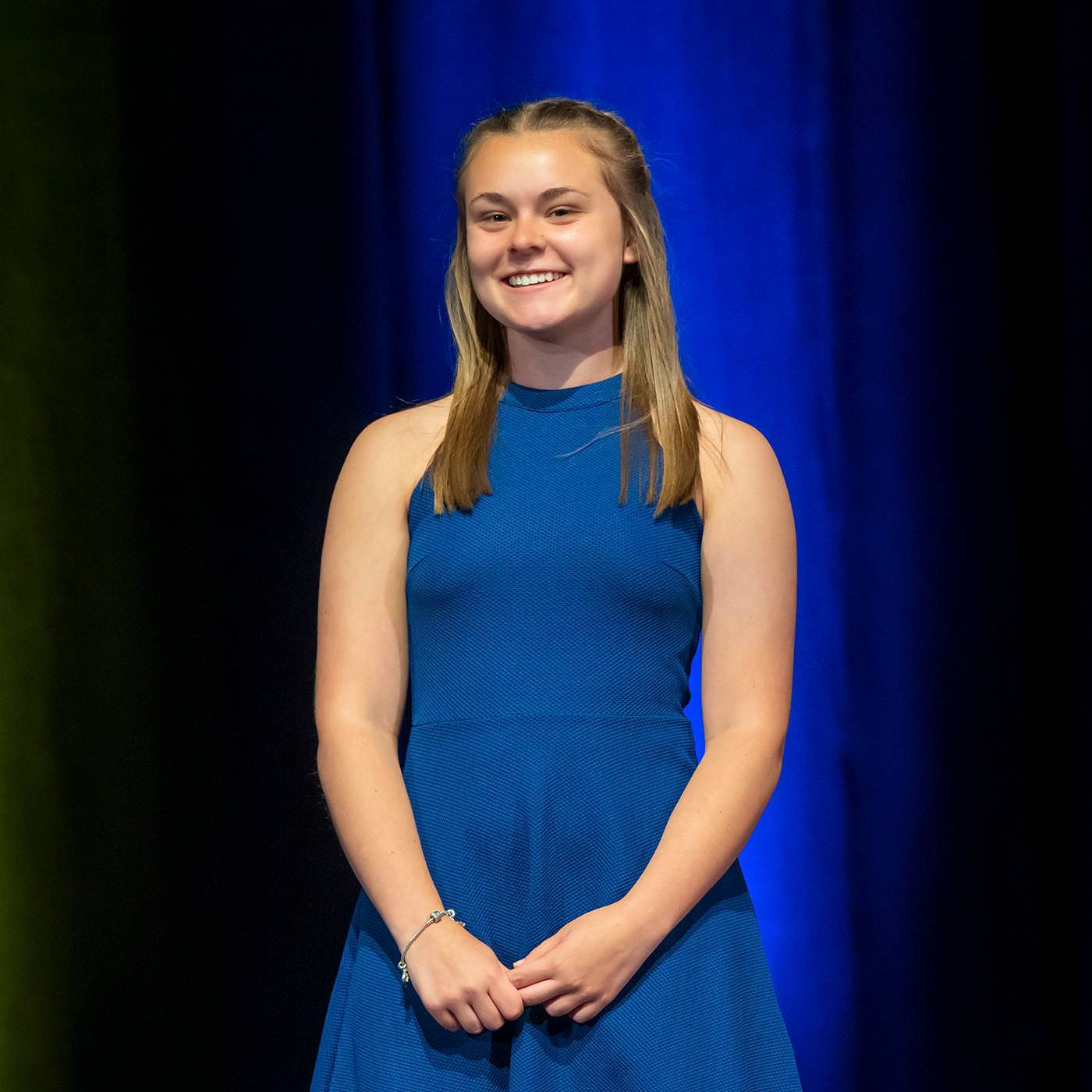 Woman in blue dress smiles at camera.