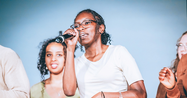 A member of the Gospel Choir holding a microphone and singing. 