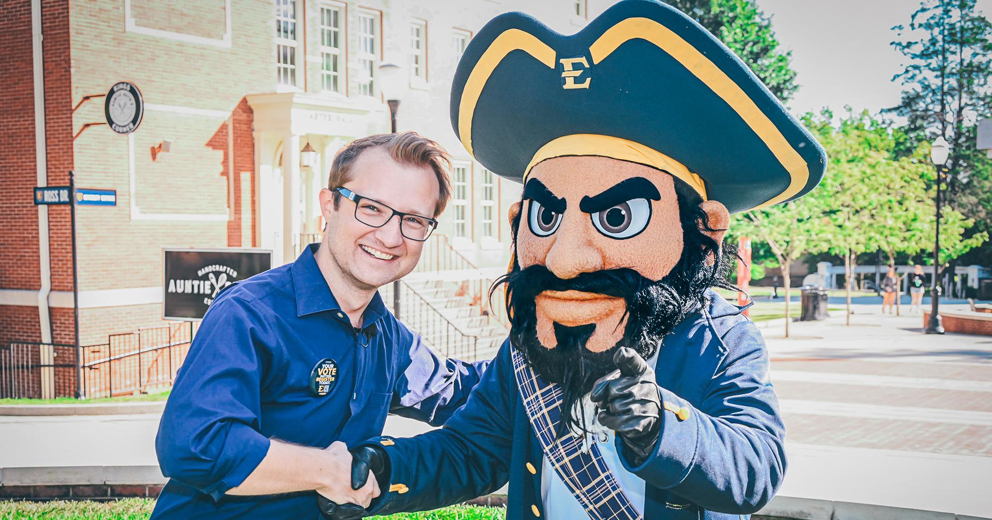 ETSU employee Nathan Farnor shakes Bucky's hand and smiles at the camera