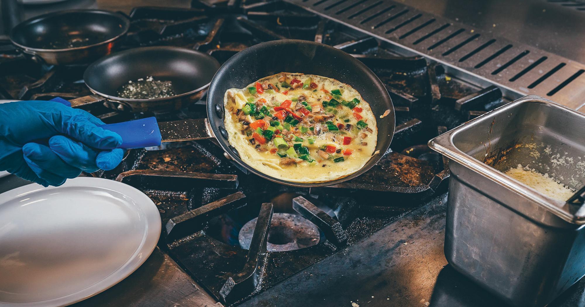 A chef cooking an omelet in a skillet on the stove.