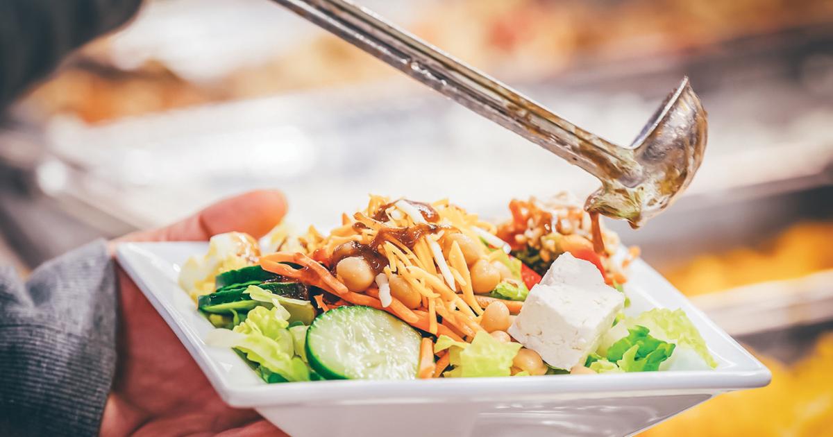 A person ladles dressing on to her salad.