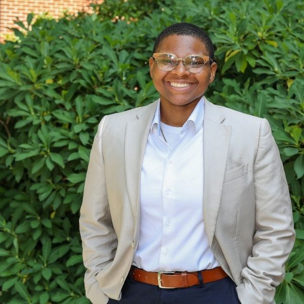 Pharrin C., MPH student, stands outside in front of some shrubbery.