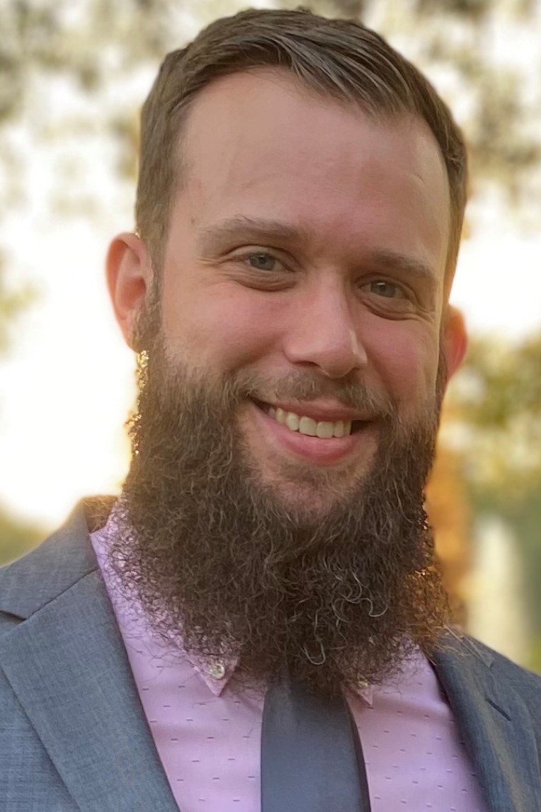  A headshot of Derrick Nealy in a suit and tie.