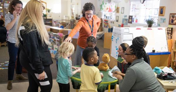 Two teachers work with a group of young children at a children's day center. 