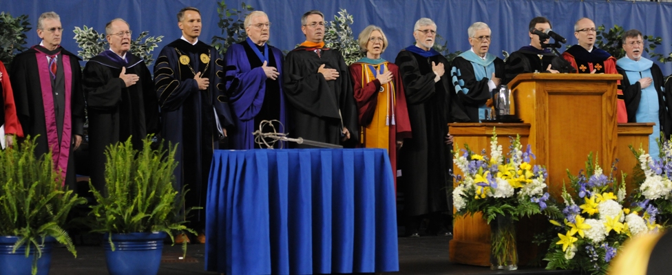 Stage party members reciting Pledge of Allegience at commencement