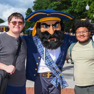 Two students smile with Bucky on the first day of classes.