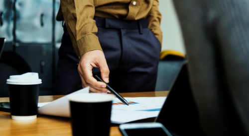 person pointing pencil at a document on a table